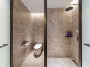 A modern bathroom with a shower, toilet, and marble walls.