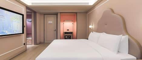 Habitación de hotel con una cama grande, un televisor de pantalla plana montado en la pared, una mesita de noche y una mesilla.