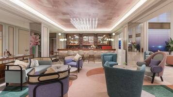A spacious lounge area with a high ceiling, a bar with a view, and comfortable seating.