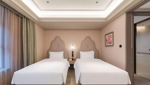 Una habitación de hotel con dos camas, una mesita de noche, una lámpara y un cuadro en la pared.