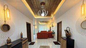 Un couloir moderne avec un plafond en bois, un lustre et un canapé rouge en arrière-plan.