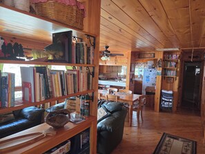 Un interno accogliente con pavimento in legno, zona pranzo, angolo cottura e una libreria piena di libri.