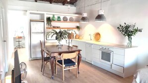 Eine moderne Küche mit Holztisch, weißen Schränken und Pendelleuchten.