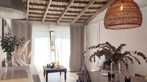 Ein Essbereich mit Holztisch, Stühlen, einer Pendelleuchte und Blick ins Freie durch ein Fenster.