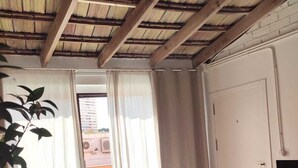 Ein Zimmer mit Holzboden, einer weißen Tür, einem kleinen Tisch mit Fernbedienung und einer Pflanze.