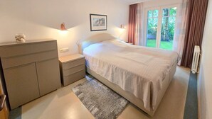 Una camera da letto con un letto, comodini, una cassettiera, un quadro incorniciato e una finestra con tende.