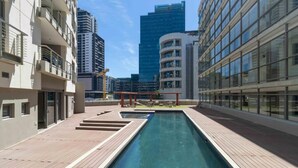 Ein Dachpool mit Holzterrasse, umgeben von modernen Gebäuden.