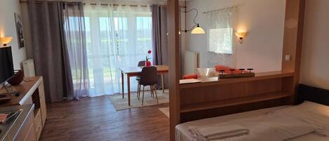 Un dormitorio con cama con dosel, un escritorio con silla y vistas al exterior a través de amplios ventanales.