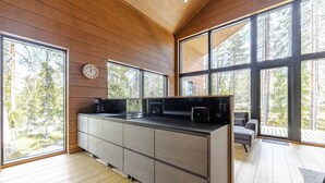 A modern kitchen with large windows, a built-in stove, and a dining area with a sofa.