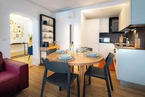 Eine moderne Küche mit weißen Schränken, einem Holzespeisetisch mit blauen Stühlen und einem roten Sofa.