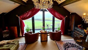 A cozy room with a large window, a chandelier, and a fireplace. - The View, Luxury Retreat, Outstanding views over the countryside & Hebden Bridge (Cragg Vale)