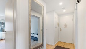 A hallway with a large mirror, a door, and a brown carpet. - Apartment 'Melody' with Balcony and Wi-Fi (Oberkochen)