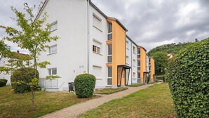 A multi-story residential building with a white facade and orange accents, surrounded by greenery and a paved pathway. - Apartment 'Melody' with Balcony and Wi-Fi (Oberkochen)