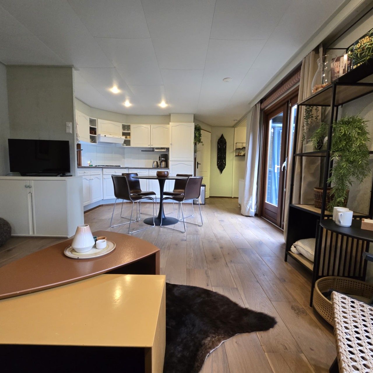 A modern living space with a dining area, kitchen, and a television.