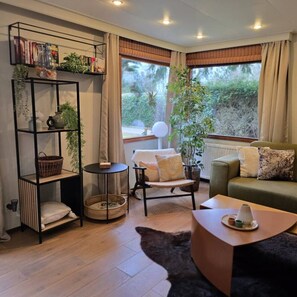 Un salon confortable avec un canapé, une table basse, une bibliothèque et une fenêtre avec des rideaux.