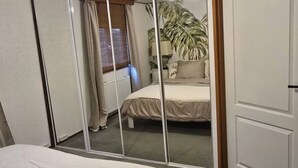 Una camera da letto con un letto, un armadio, uno specchio e una finestra con tende.