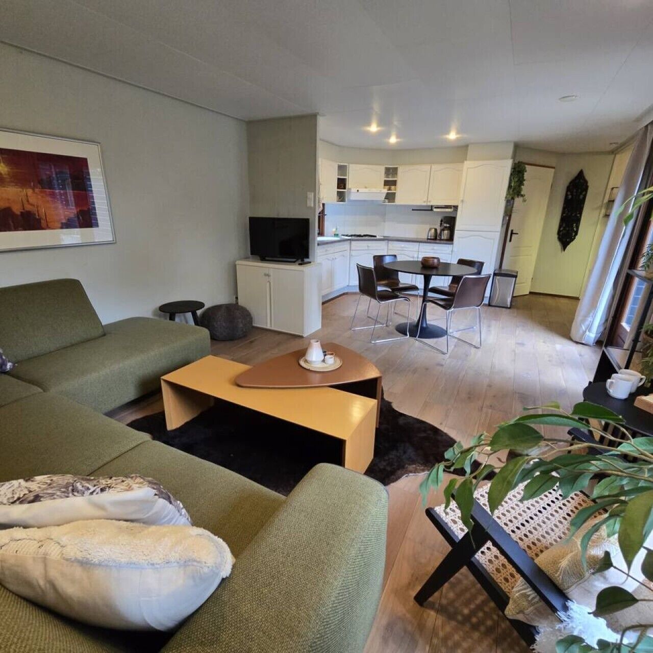 Uma sala moderna com um sofá, uma mesa de centro e um espaço de jantar com cadeiras.