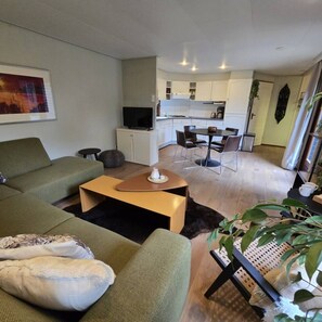 Un salon moderne comprenant un canapé, une table basse et un coin repas avec des chaises.