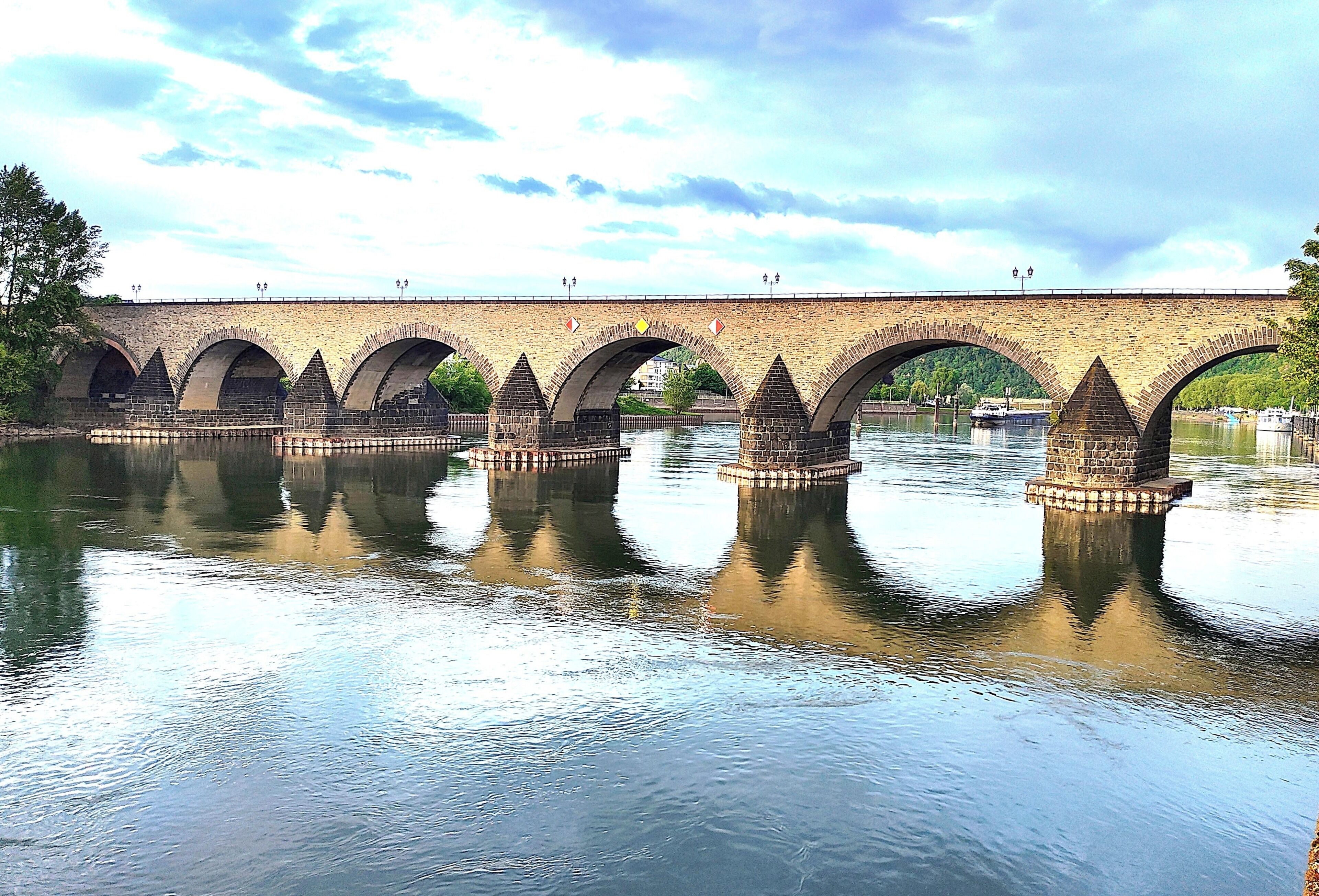 A stone bridge with multiple arches over a calm river.