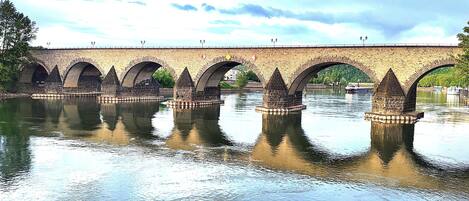 A stone bridge with multiple arches over a calm river.