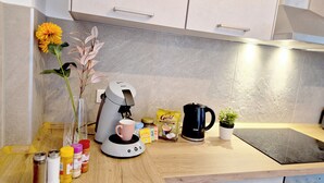 Una cocina con cafetera, taza, planta y condimentos en la encimera.