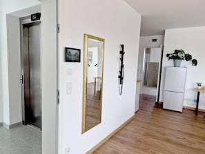 A hallway with a door marked '2L', a mirror, a knife on the wall, a small table, and a refrigerator. - Modern city apartment with parking space on the doorstep (Koblenz)