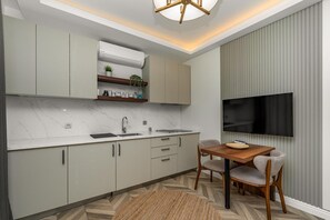 Eine moderne Küche mit integriertem Fernseher, einem Essbereich mit Holztisch und -stühlen sowie einem Fischgrätenparkettboden.