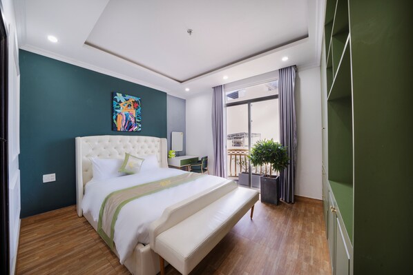 Une chambre d’hôtel moderne avec un grand lit, un bureau, une plante en pot et un balcon avec des rideaux.