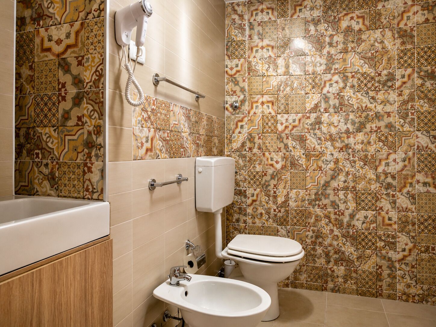 A bathroom with a bathtub, a bidet, a toilet, and a hand dryer.