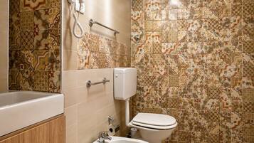 A bathroom with a bathtub, a bidet, a toilet, and a hand dryer.