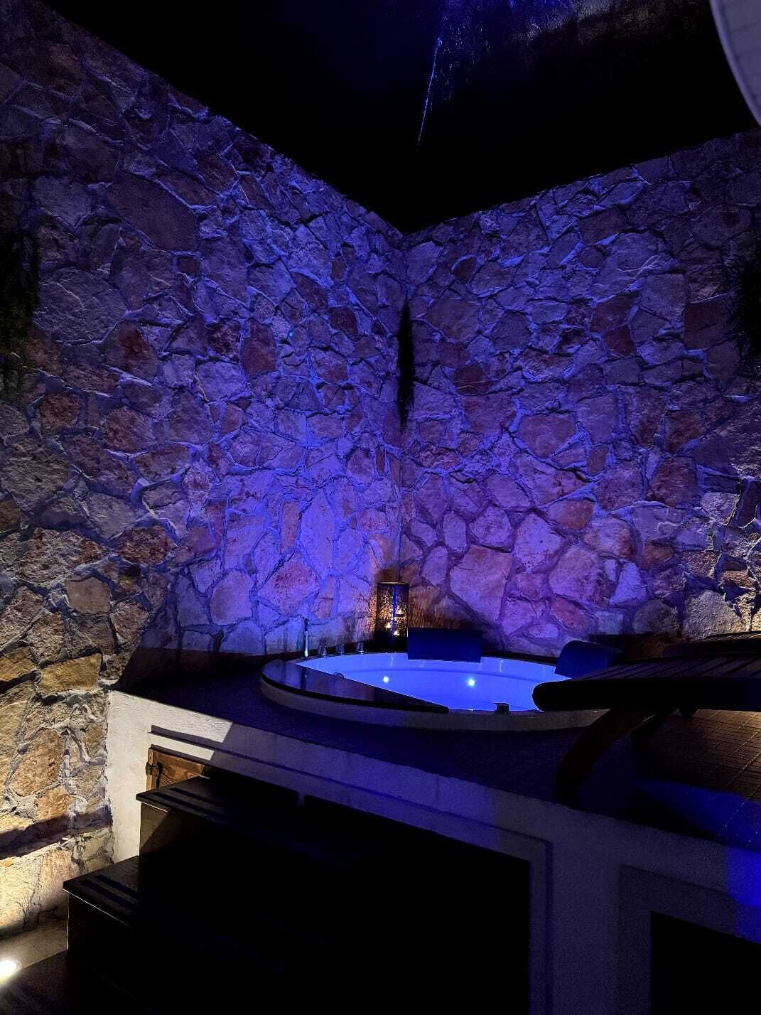 Een wellnessruimte met stenen muren en een jacuzzi.