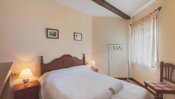 Una camera d'albergo con un letto in legno, due lampade sui comodini, un armadio e una sedia.