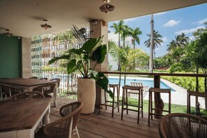 A covered outdoor area with a pool, wooden furniture, and a large potted plant. - 2BR Oceanfront • Steps to Beach • Sol de Arena B6 (Las Terrenas)