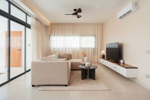 Ein modernes Wohnzimmer mit einer Couch, einem Fernseher und einem Deckenventilator.