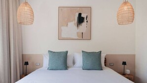 Ein Hotelzimmer mit einem großen Bett, zwei Nachttischlampen und einem an der Wand hängenden abstrakten Gemälde.