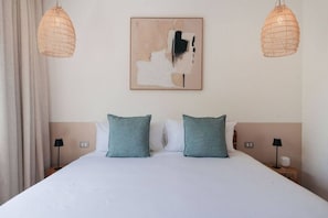 Ein Hotelzimmer mit einem großen Bett, zwei Nachttischlampen und einem an der Wand hängenden abstrakten Gemälde.