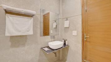 A bathroom with a marble wall, a white sink, a mirror, and a wooden door.