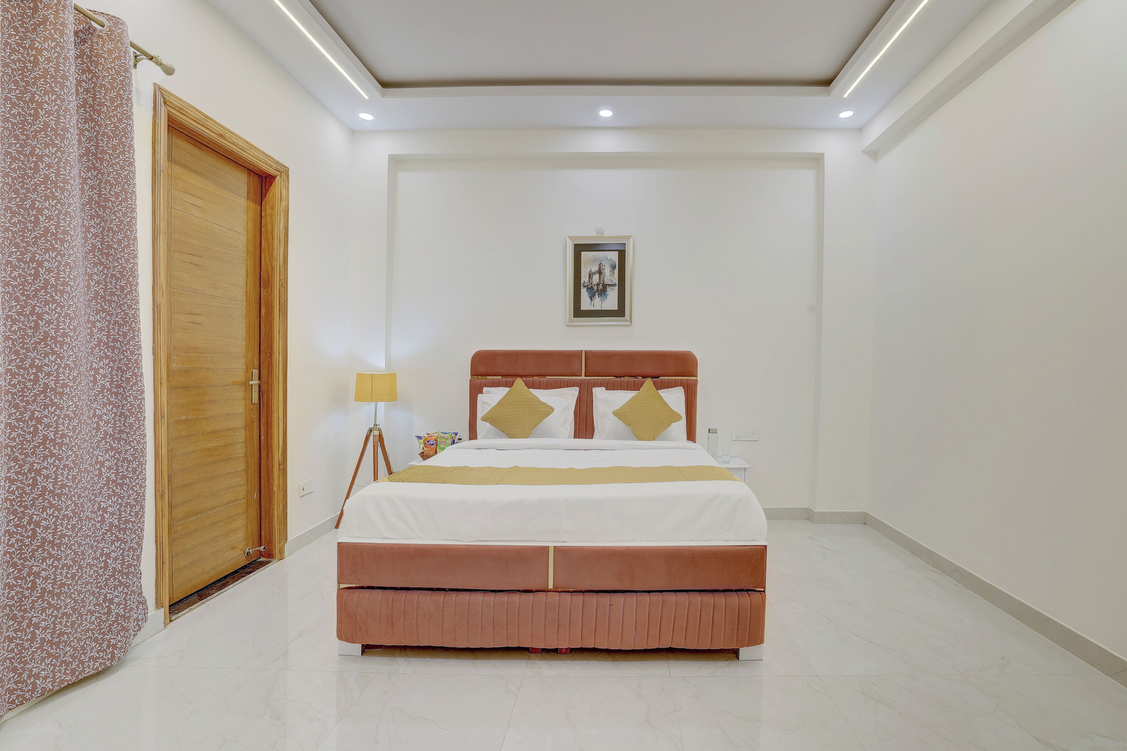 Una camera da letto con un letto, una porta in legno, un quadro appeso al muro e un comodino con una lampada.