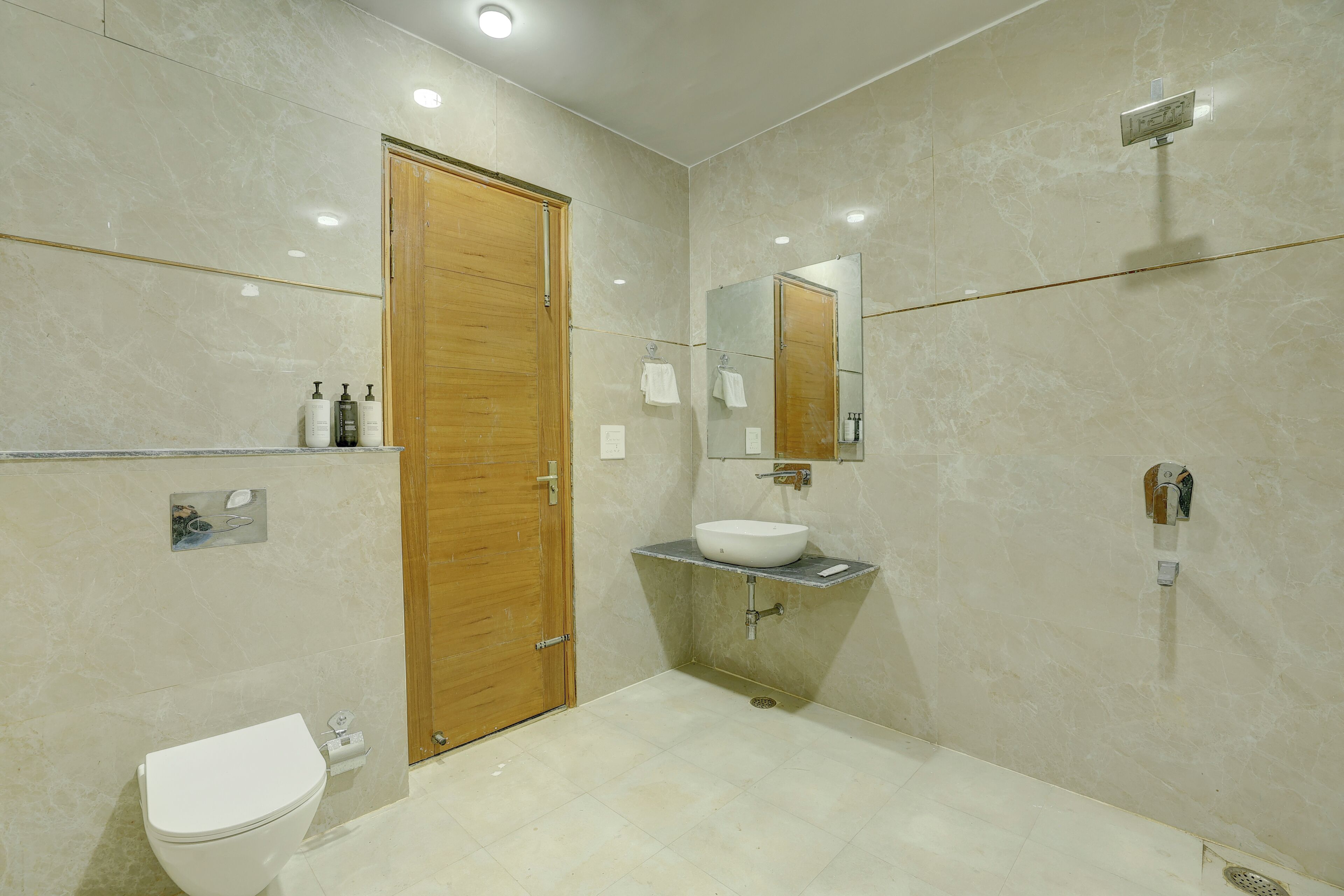A bathroom with a wooden door, a white toilet, a sink with a mirror, and a shower.