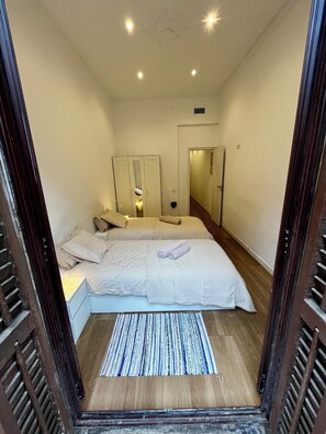A bedroom with a bed, bedside tables, a mirror, and a door leading to another room. - Barcelona center family apartment 3 (Barcelona)