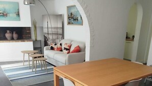 Een moderne woonkamer met een houten eettafel, een witte bank en een open haard.