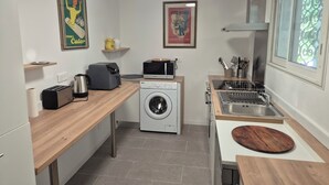 Een kleine keuken met een wasmachine, magnetron, broodrooster en een spoelbak met afwassysteem.