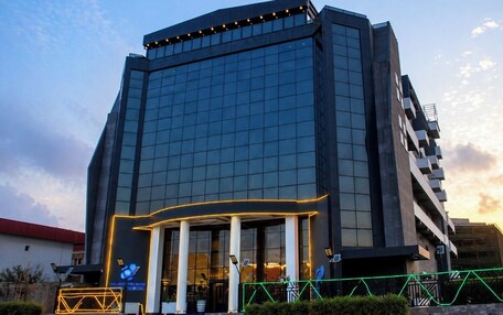 A modern hotel with a glass facade, a prominent entrance with columns, and illuminated signage.