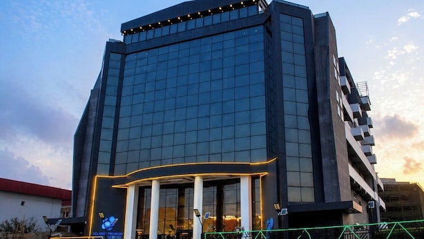 Un hôtel moderne doté d’une façade en verre, d’une entrée imposante avec des colonnes et d’une enseigne lumineuse.