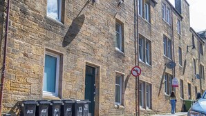 A stone building with multiple windows and doors, a no parking sign, and several trash bins along the street. - Cosy City Centre Flat | Summer Retreat | Sleeps 2 (Inverness)