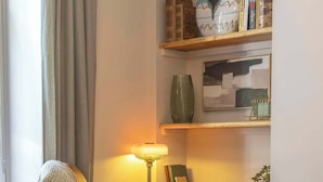 A room with a desk, chair, lamp, and shelves with books and decorative items. - Cosy City Centre Flat | Summer Retreat | Sleeps 2 (Inverness)