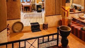 A rustic interior with a wooden ceiling, a hanging light fixture, a staircase, and a view into another room. - Riad Pizzeria Marhaba (Ait Sedrate Jbel El Soufla)