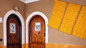 A hallway with wooden doors, a patterned rug, and a helmet on the floor. - Riad Pizzeria Marhaba (Ait Sedrate Jbel El Soufla)