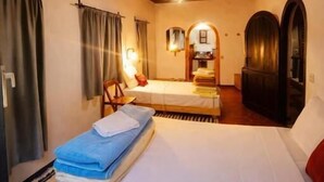 A bedroom with a wooden ceiling, a bed with white and blue bedding, a chair, and a mirror. - Riad Pizzeria Marhaba (Ait Sedrate Jbel El Soufla)