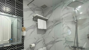 Une salle de bain avec un lavabo, des toilettes et une douche, le tout en marbre.